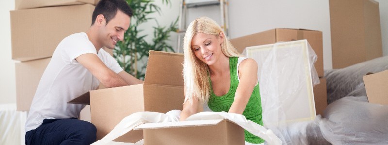 young couple packing their household in cardboard boxes