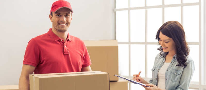 a professional with a cardboard box and a woman writing something on a paper