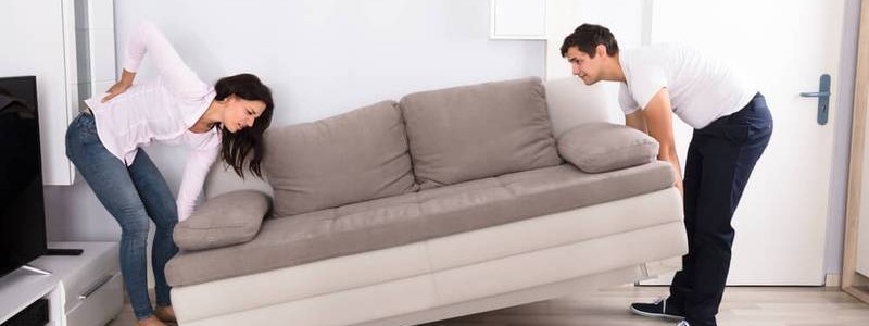 young couple trying to move a heavy couch