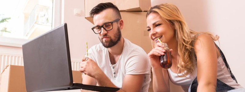 young couple sitting on the floor and searching for something on a laptop