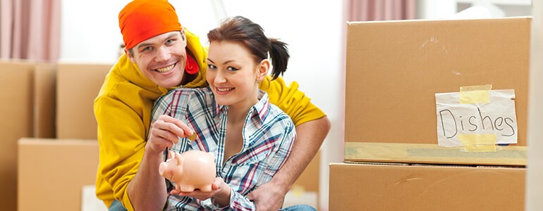 young couple sitting on the floor and holding a piggybank