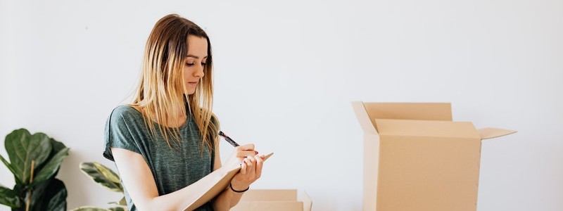 young woman writing something on a notebook and preparing to relocate