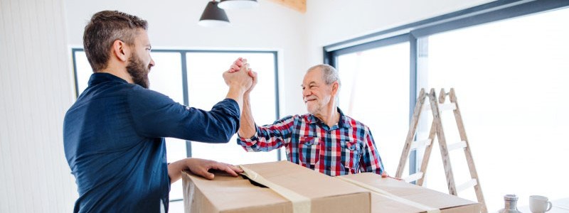 young man and his father packing up a cardboard box