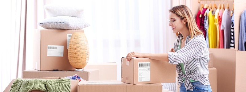 young woman packing clothes while relocating