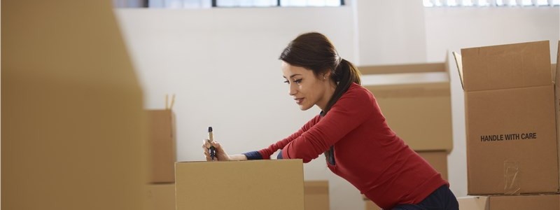 young woman writing down something on a cardboard box
