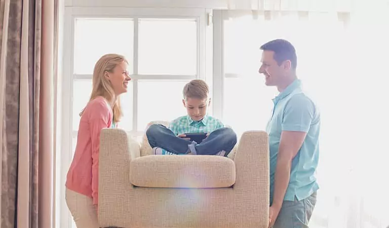couple trying to lift a heavy couch and a kid sitting on it