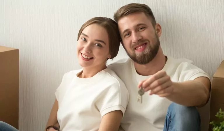 couple sitting inside of their new house and showing a key