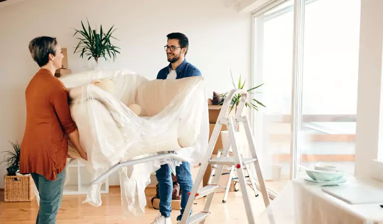 young couple trying to move a couch.