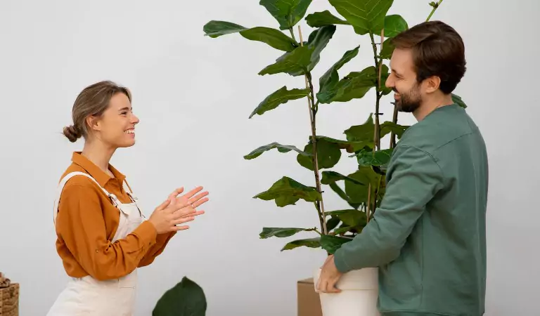 young man holding a house plant talking with a woman