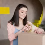 woman packing up cardboard boxes during a move