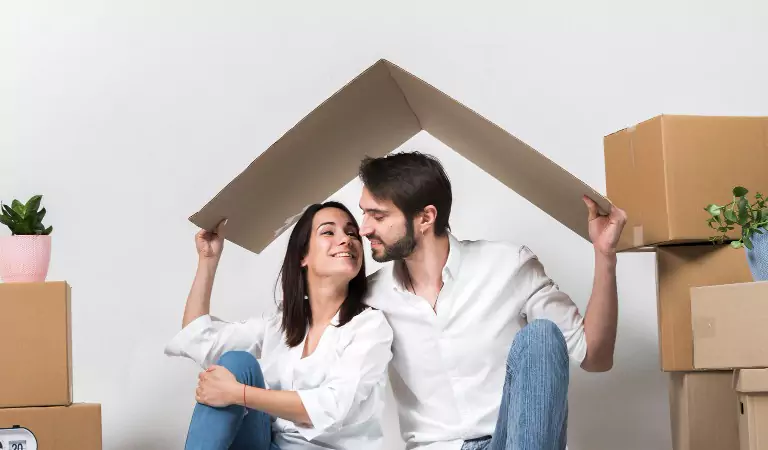 couple under a cardboard sheet sitting on the floor