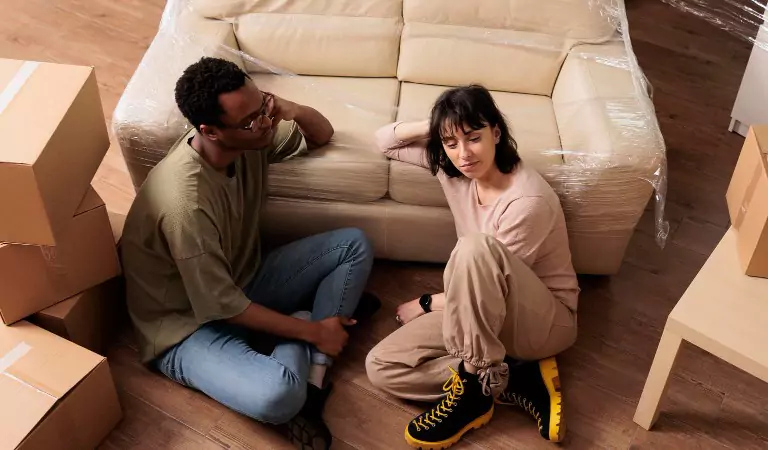couple sitting inside of a house and looking stressed