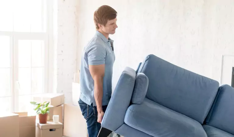 young man lifting a heavy couch