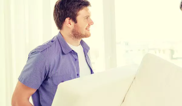 young man lifting a heavy couch