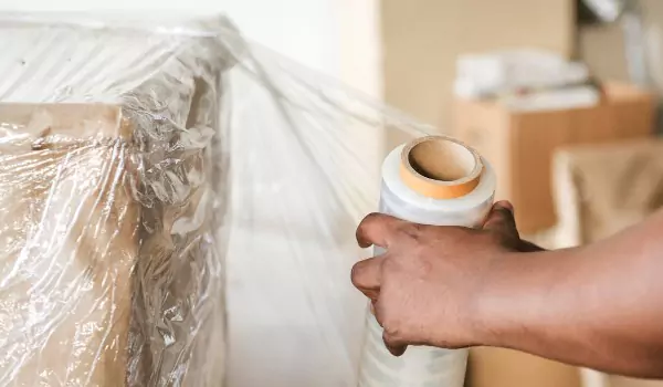 cropped picture of a person packing a cardboard box with plastic