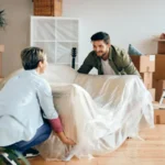 Two people holding a sofa